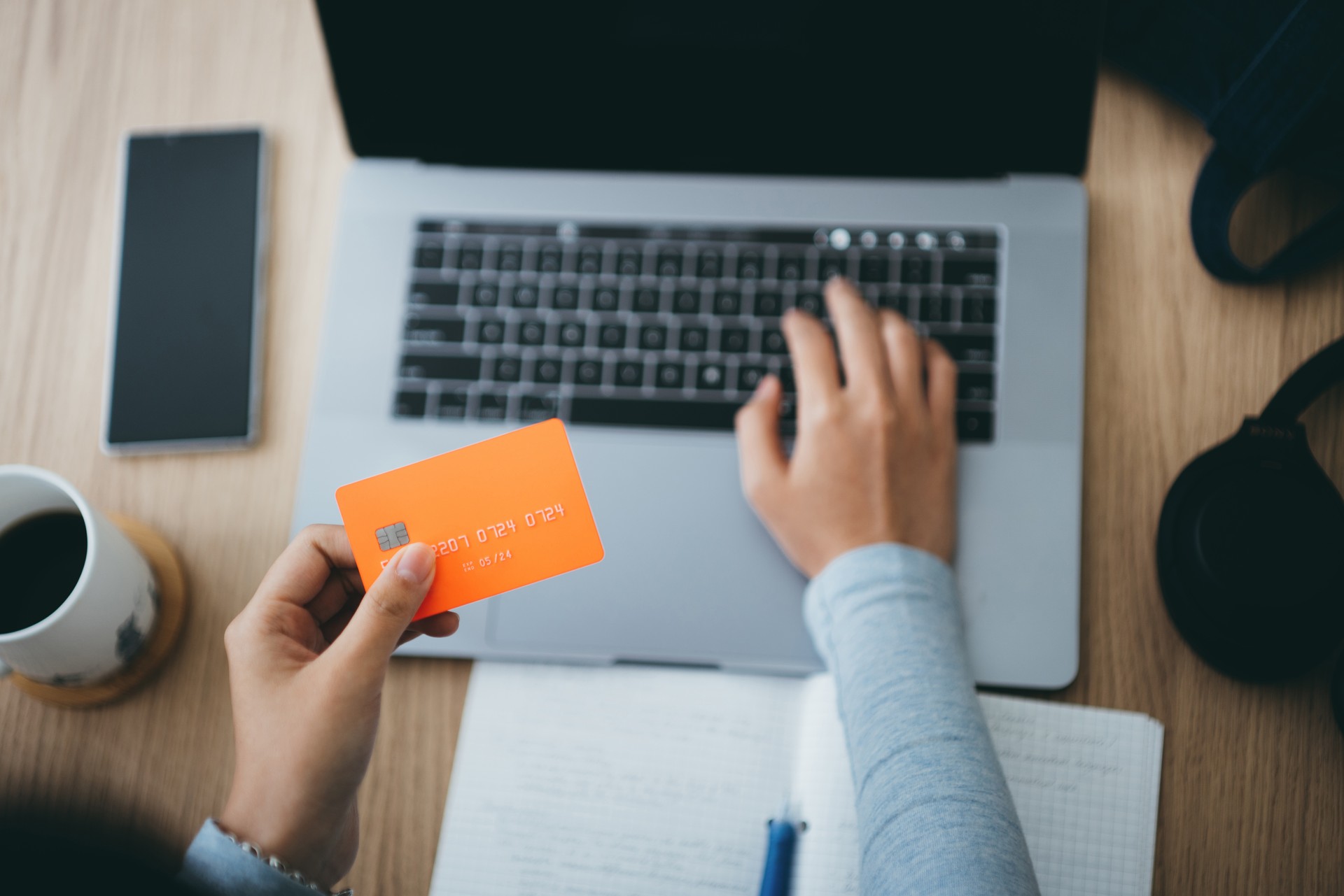 Asian woman using laptop and holding a credit card, close-up